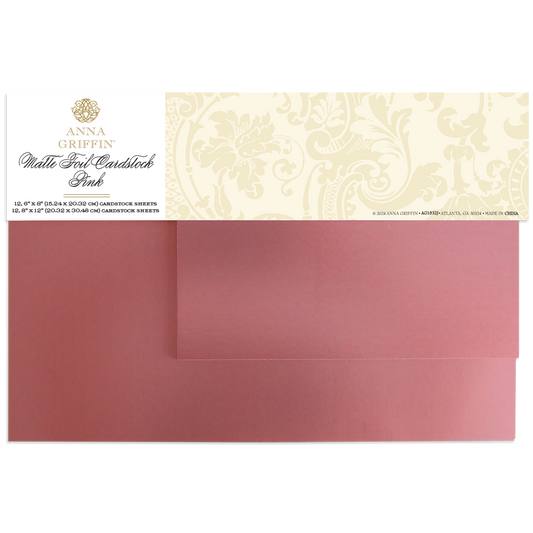 Two sheets of Luxury Matte Foil Cardstock Pink, partially overlapping and topped with a decorative Anna Griffin label, perfect for diecutting and embossing projects.