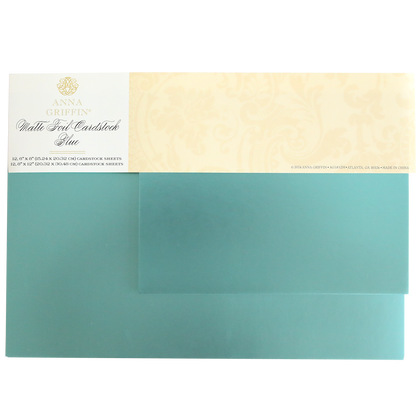 The Luxury Matte Foil Cardstock Blue by Anna Griffin, featuring a decorative beige label with text and floral patterns, is perfect for embossing and die-cutting.