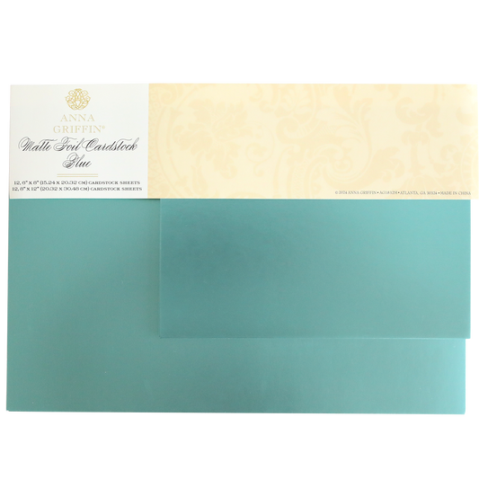 The Luxury Matte Foil Cardstock Blue by Anna Griffin, featuring a decorative beige label with text and floral patterns, is perfect for embossing and die-cutting.