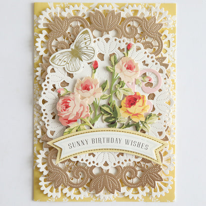 Celebrate a birthday with a decorative card crafted using the 12″ Regal Trimmings Border Dies and Rose Gold Matte Foil Cardstock, featuring layered lace borders, pink and yellow roses, an elegant gold butterfly, and the message “Sunny Birthday Wishes” on a banner at the bottom.