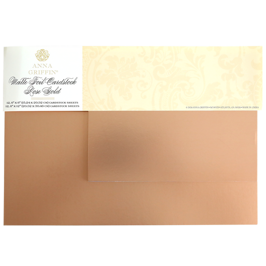 Two sheets of Luxury Matte Foil Cardstock Rose Gold partially overlap, featuring a decorative Anna Griffin label on the top left—ideal for embossing or die-cutting elegant crafts.