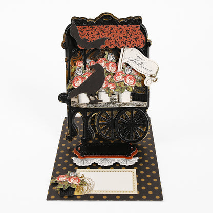 Halloween-themed pop-up card crafted from Luxury Matte Foil Cardstock Black, featuring a black cart, roses, two crows, a “Happy Halloween” tag, and a gold polka dot background—perfect for diecutting enthusiasts.
