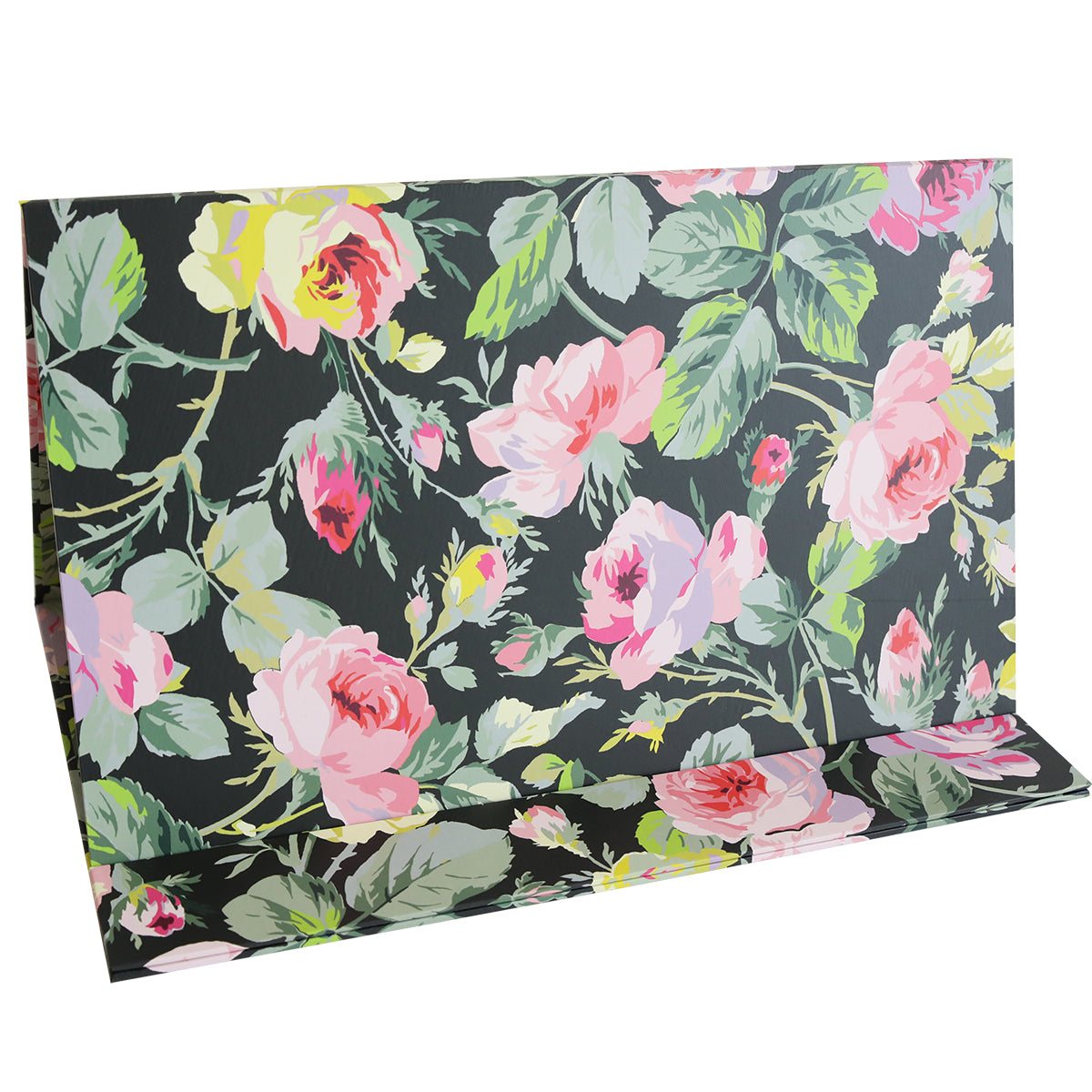 A folded piece of the Magnetic Die Stand Grace Black, adorned with a floral pattern featuring pink and yellow roses with green leaves on a dark background, sits perfectly in the craft room, adding a touch of elegance to the organized crafting space.