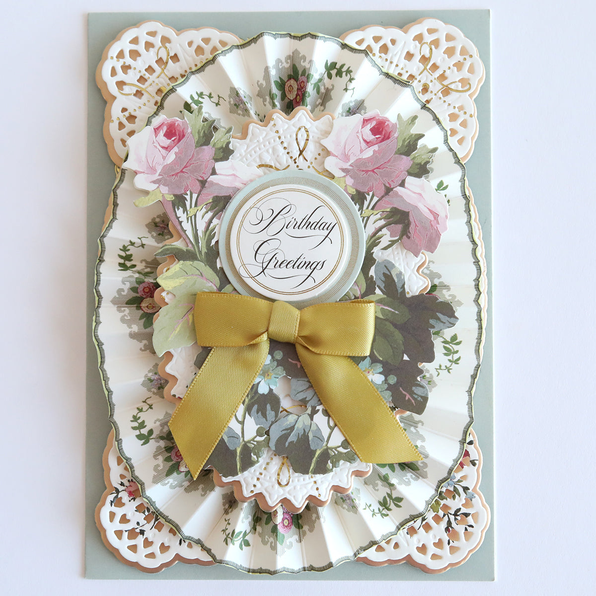 The Floral Paper Anthology offers a decorative birthday card made from floral cardstock, adorned with pink roses, a gold bow, and intricate paper lace details. Ideal for handmade card enthusiasts or to bring elegance to scrapbooks.