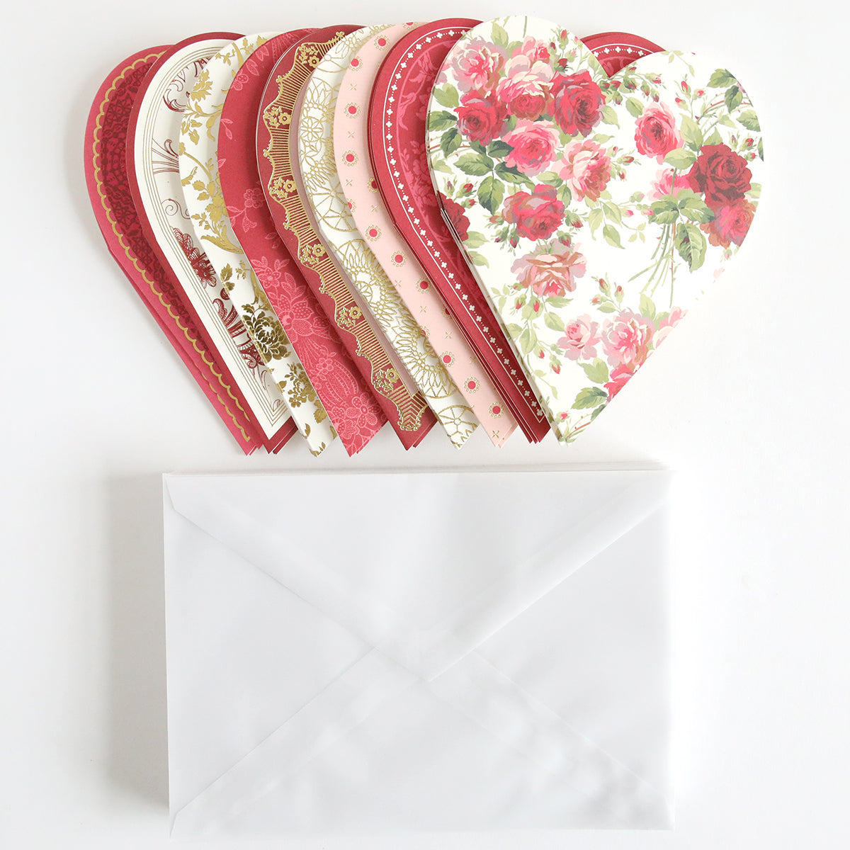 A set of Heart Shaped Cards with Envelopes 36 count, featuring floral and patterned designs, sits atop a plain white envelope, primed to convey your heartfelt message. These delightful cards offer a blank interior, providing limitless opportunities for personalization against the pristine white backdrop.