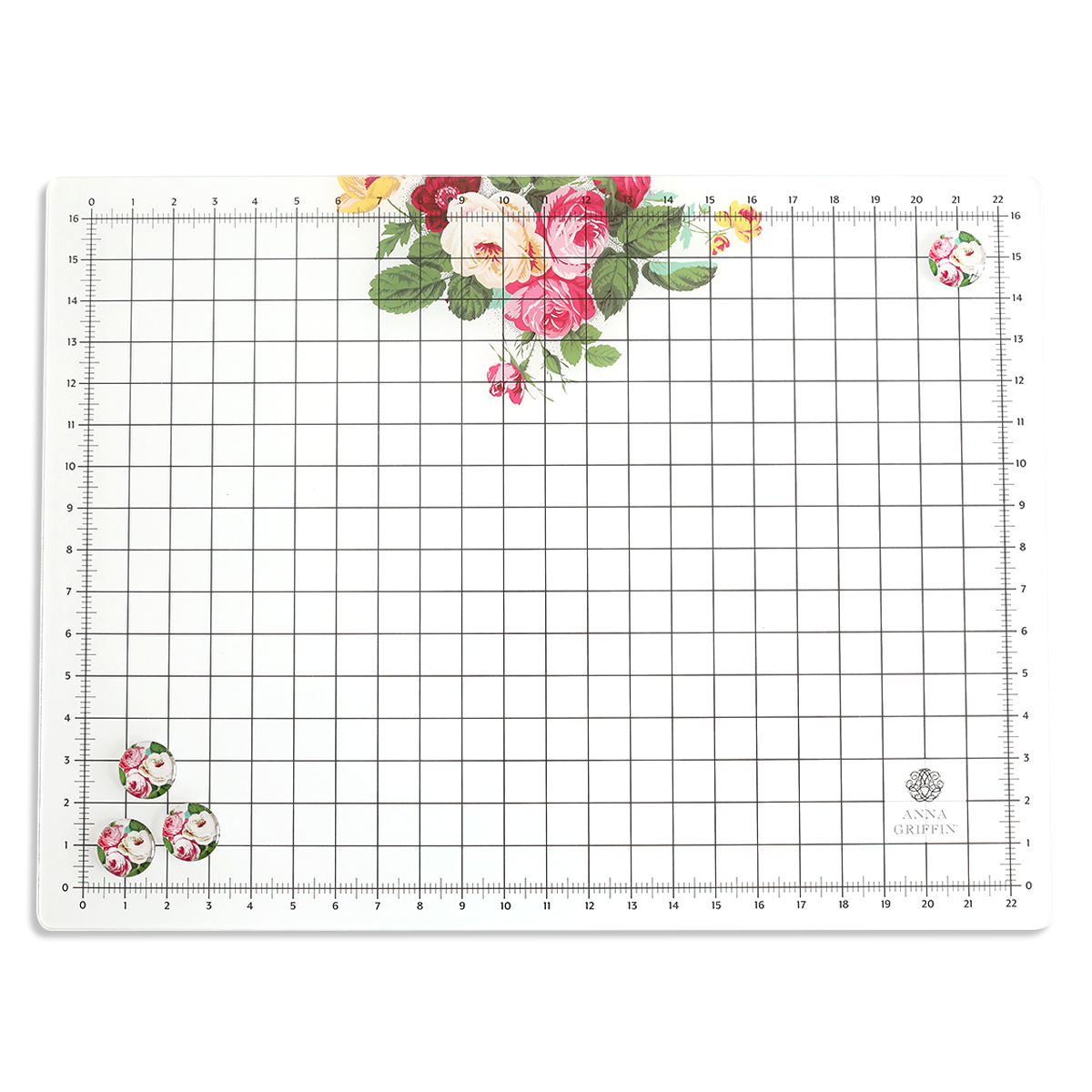 The Glass Magnetic Craft Mat 16 x 22 is a rectangular mat with grid and ruler markings, featuring clusters of pink, red, and yellow flowers in two corners and the "Anna Griffin" logo in the bottom right.