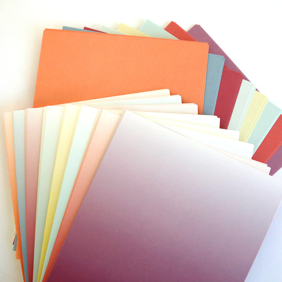 The Blooms Flower Mold, Stamps and Dies set features pastel-colored paper sheets in a fan shape—ideal for crafting paper flowers or using with cutting dies on a white surface.