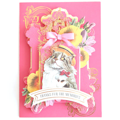 The Glorious Foil Rub Ons Gold features a delightful cat illustration donning a hat, bowtie, flowers, and pink bow. With gold foil accents and the message "Thanks Fur the Memories," it's ideal for craft projects or expressing heartfelt gratitude.