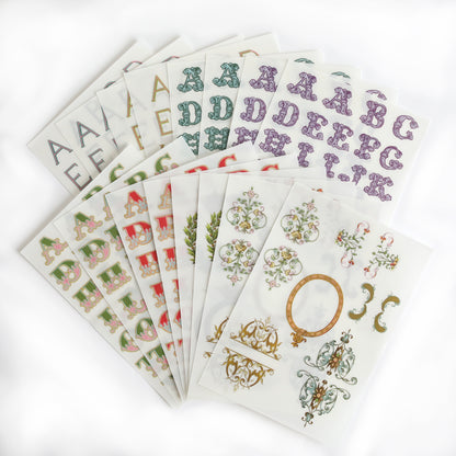 The Fancy Alphabet Rub On Transfers, ideal for scrapbooking or cardmaking, are fanned out on a white background.