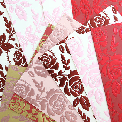 Luxury Tonal Foil Heartfelt Cardstock sheets in pink, red, cream, and gold tones feature embossed rose, floral, and leaf patterns and are arranged in a fan shape.