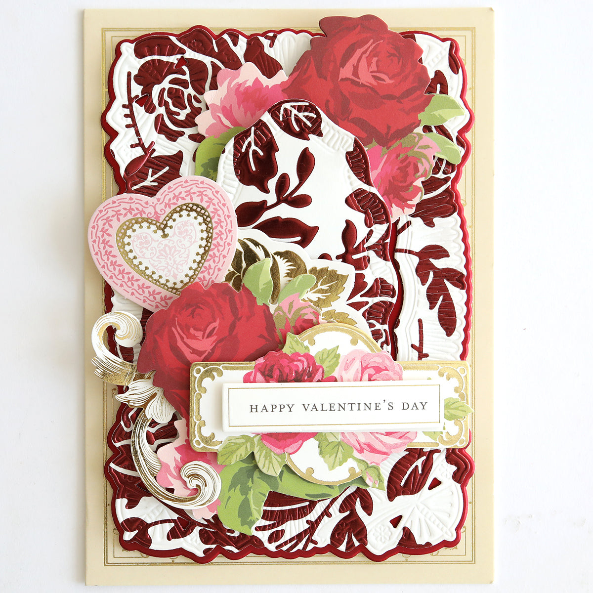 A decorative Valentine's Day card with red roses, green leaves, a pink heart, and "Happy Valentine's Day" text on Luxury Tonal Foil Heartfelt Cardstock featuring an elegant embossed rose pattern.