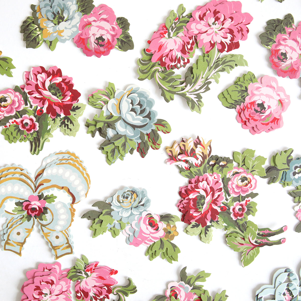 Phoebe Die Cut Embellishments, featuring vintage-style pink, red, and blue flowers with green leaves, are scattered on a white background.
