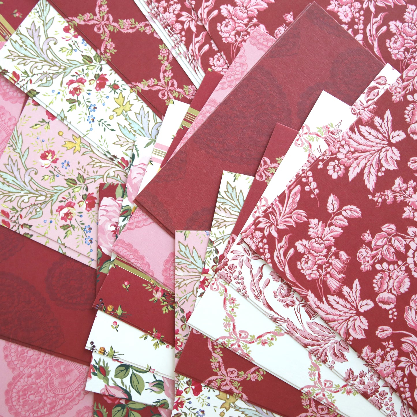 Heartfelt Cardstock features rectangular, double-sided sheets in red, pink, and white tones with floral and decorative patterns, arranged in an overlapping display.