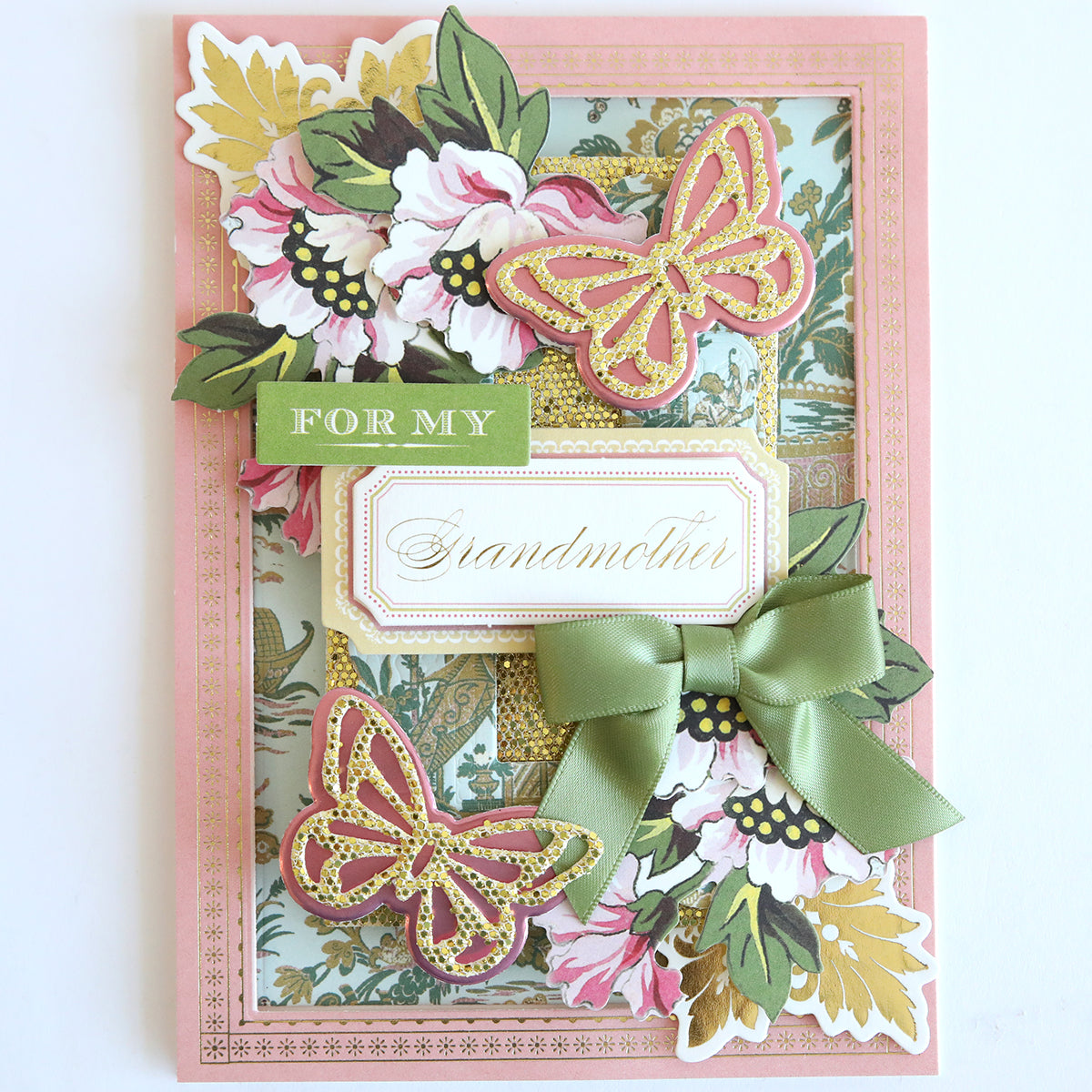 A decorative card made with Diamond Glitter 12x12 Cardstock 12 sheets, featuring pink and gold butterflies, florals, a green bow, and a "For My Grandmother" label—an ideal sparkly touch for your scrapbook supplies.