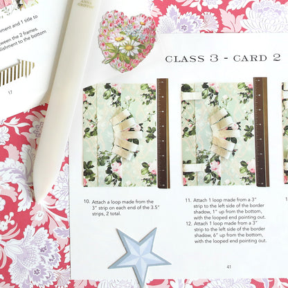 The Create Spring 2026 Printed Instructions provide step-by-step guidance with color photos to craft using a bone folder, floral-patterned paper, heart cutout, and star on a pink floral background.