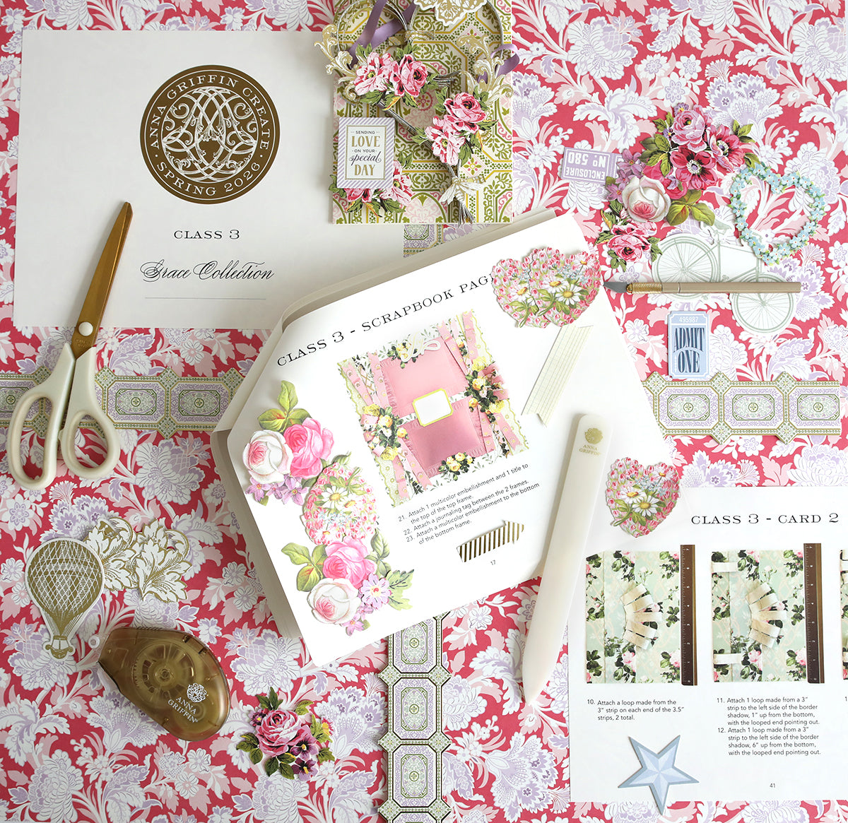 A flat lay of scrapbook supplies and color photos on a pink floral-patterned surface, featuring papers, flower cutouts, tools, the Create Spring 2026 Printed Instructions, and a "Class 3" certificate.