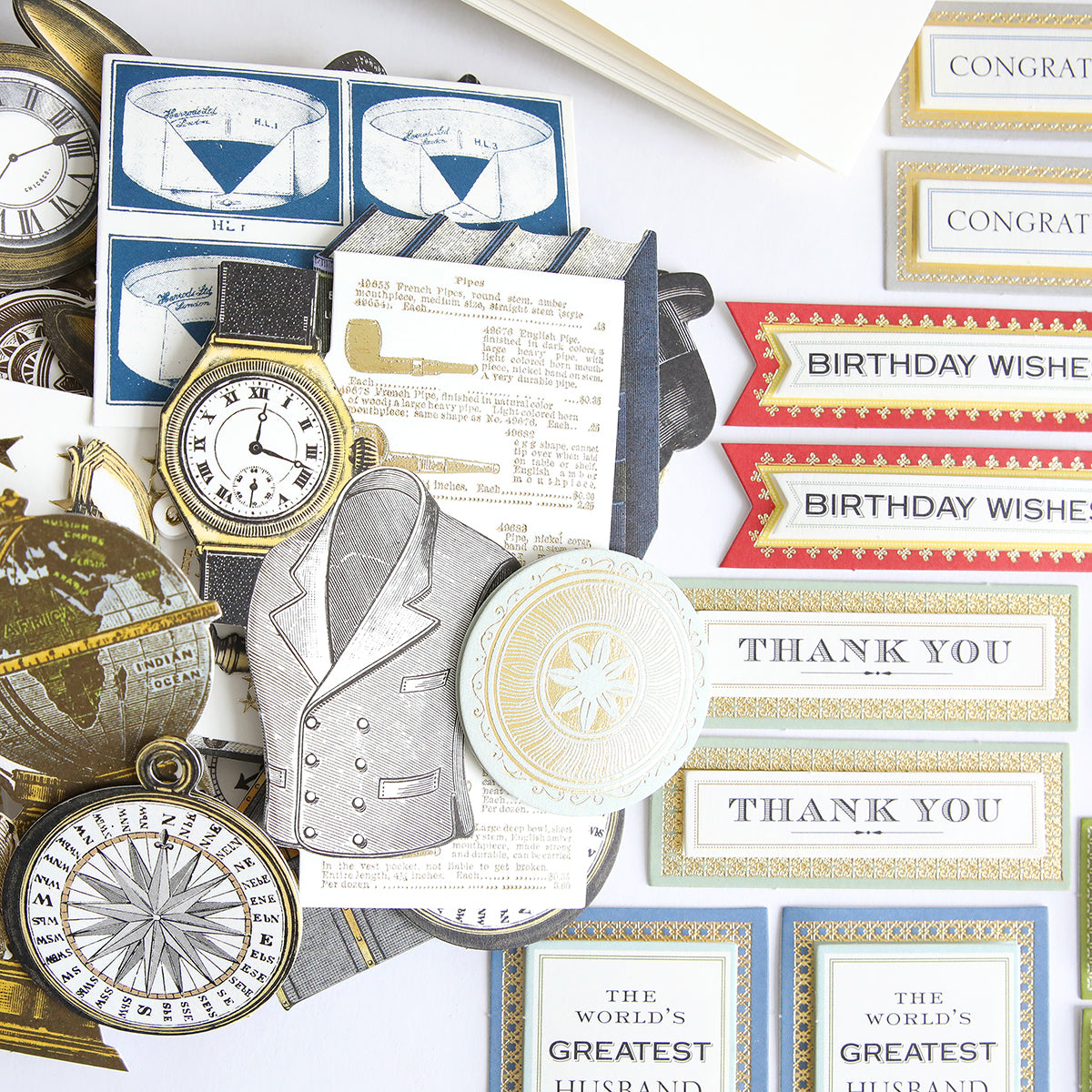 Assorted vintage-style paper cutouts from the All About Him Papercrafting Kit with Dies, featuring watches, compasses, suit jackets, and message cards like "THANK YOU" and "BIRTHDAY WISHES," displayed on a white background.