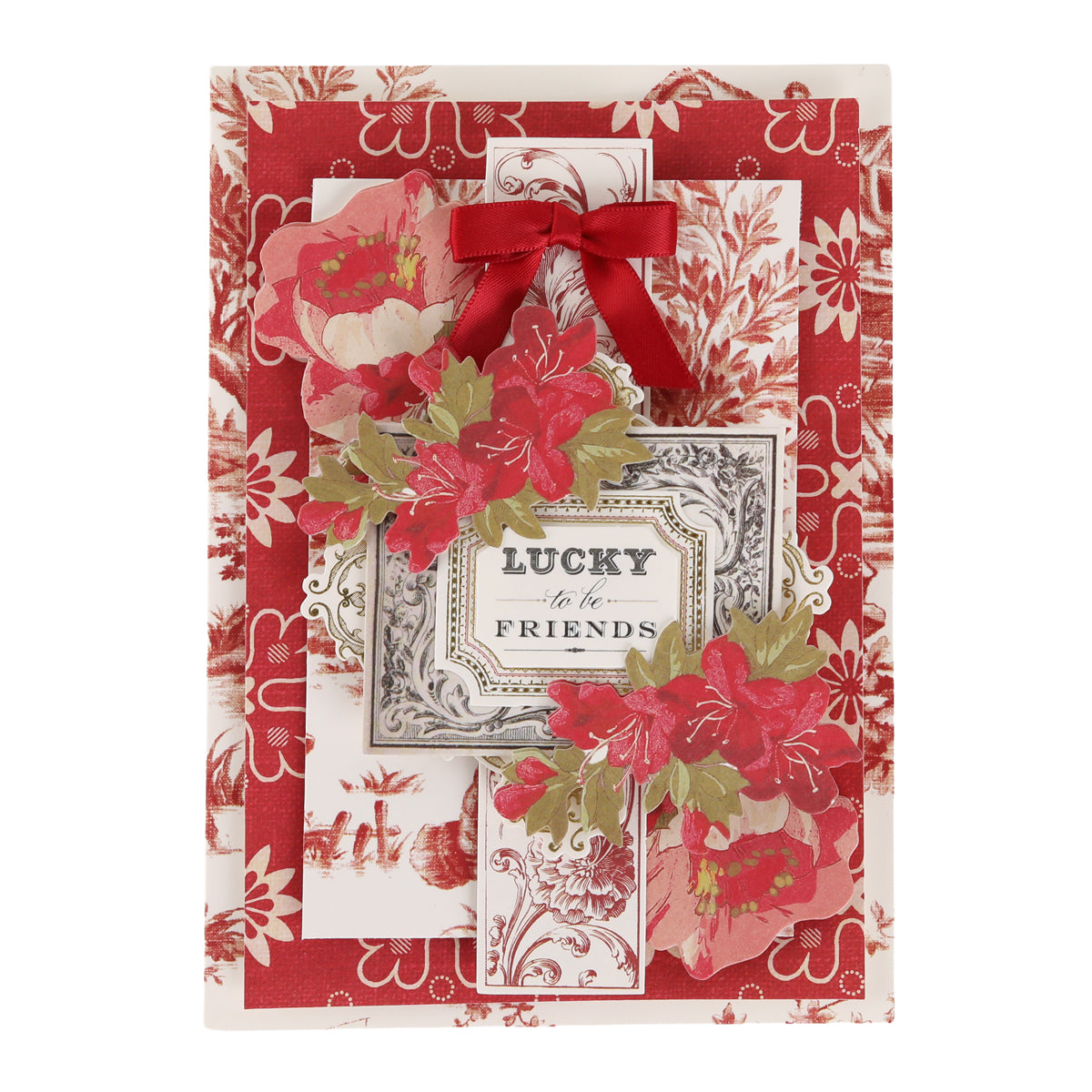 A decorative card featuring red floral patterns, a red bow, and the sentiment “Lucky to be Friends” at the center surrounded by red and green flowers, beautifully crafted with the Fleur Rouge Papercrafting Kit with Dies for a touch of vintage-inspired papercrafting charm.