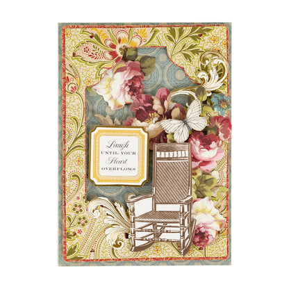 Handmade greeting card created with the Haven Papercrafting Kit with Dies, featuring floral patterns, a die-cut rocking chair, a butterfly, and a label that reads, “Laugh until your heart overflows.”