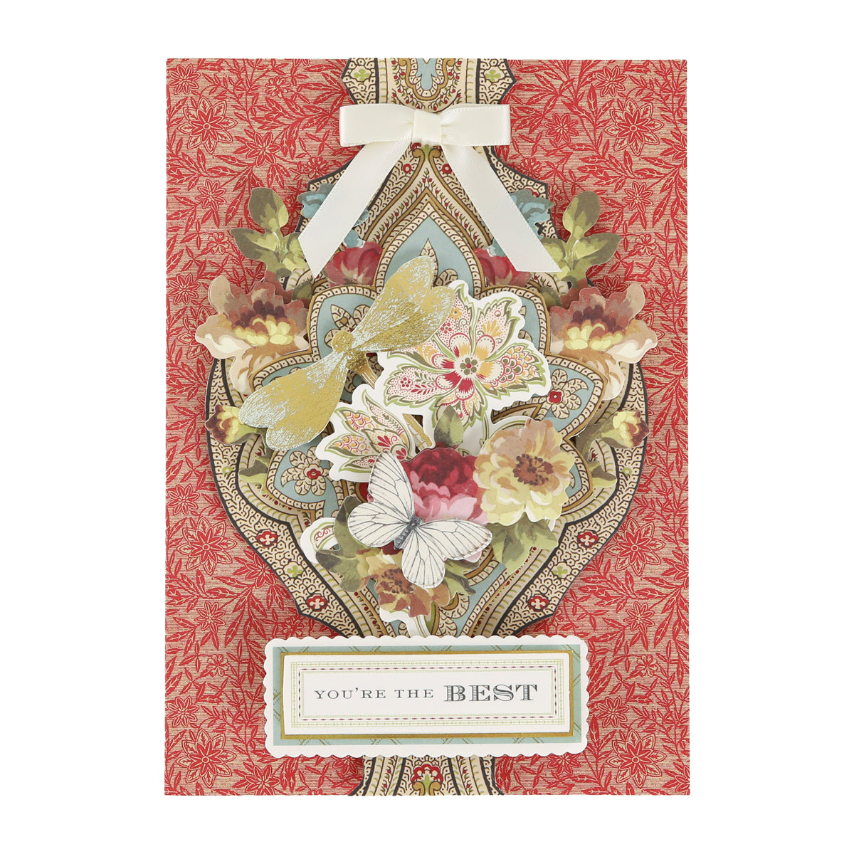 Handmade greeting card created with the Haven Papercrafting Kit with Dies, featuring a red patterned background, floral and butterfly die-cuts, a white ribbon bow, and a label reading “YOU’RE THE BEST.”