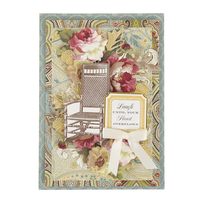 Handmade vintage card created with the Haven Papercrafting Kit with Dies, featuring a die-cut rocking chair, floral layers, and a label that reads, “Laugh until your heart overflows.”