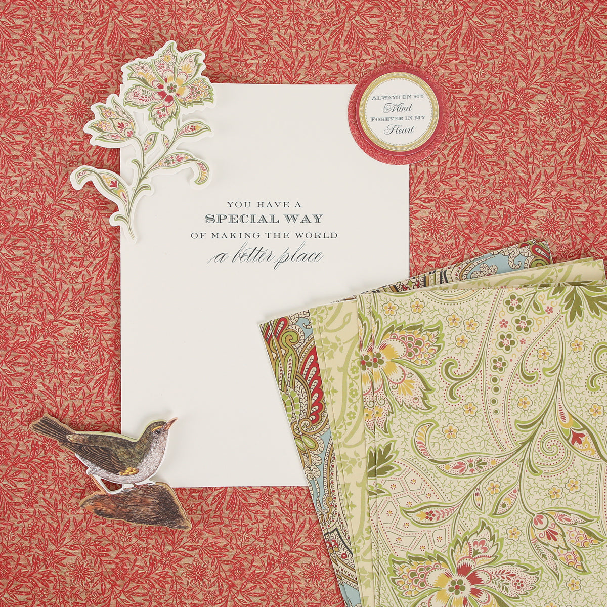 A Haven Papercrafting Kit with Dies containing patterned papers, a die-cut floral sprig, a bird cutout, and a vintage card reading, “You have a special way of making the world a better place.”