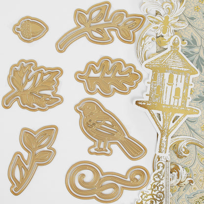 The Haven Papercrafting Kit with Dies featuring gold-toned metal leaf, bird, acorn, and birdhouse cutting dies with coordinating patterned paper cutouts for vintage card making.