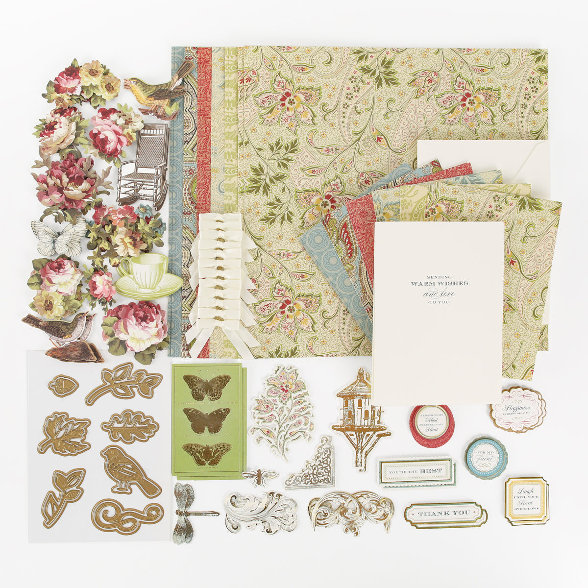 The Haven Papercrafting Kit with Dies includes vintage patterned scrapbook paper, floral die-cuts, ribbons, and small cards with messages like “Sending warm wishes and love” and “Thank you.”