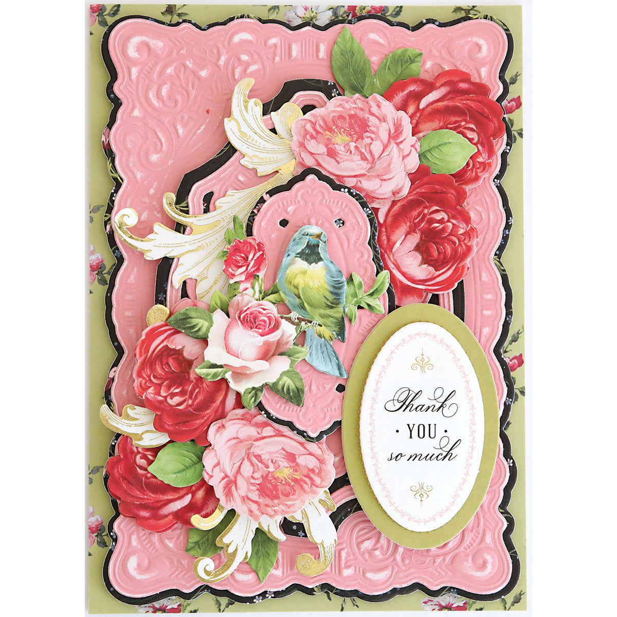 An ornate greeting card with pink embossed layers, red and pink flowers, a blue and yellow bird, scrollwork accents from the Scroll Corner Concentric Frames 3D Die Set, and an oval label reading "Thank you so much.