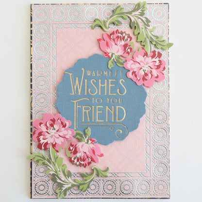 The Fabric Card Layers Antique greeting card displays "Warmest wishes to you friend," with an elegant design of pink flowers and green leaves on a pink and blue patterned background.