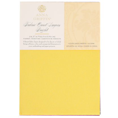 A pad of Bright Fabric Card Layers by Anna Griffin in yellow, featuring textured cardstock sheets ideal for scrapbooking and card making, with product details printed on the packaging.