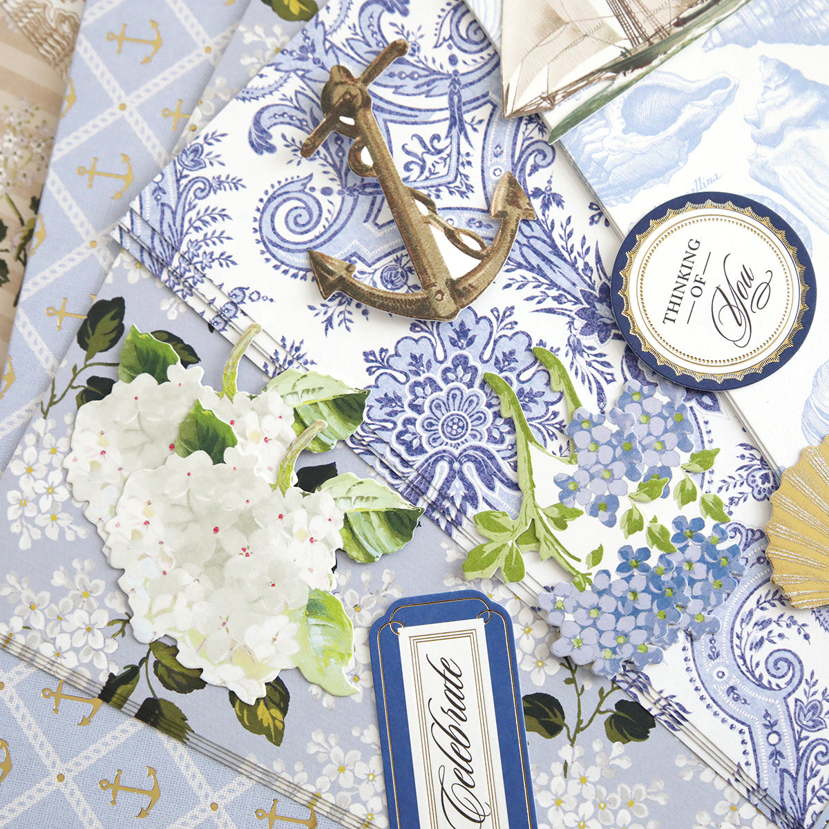 A flat lay of nautical-themed stationery featuring Summer House Cardstock and Embellishments—anchor motifs, floral cutouts, and "Celebrate" and "Thinking of You" cards—ideal for coastal scrapbooking with blue and white accents.