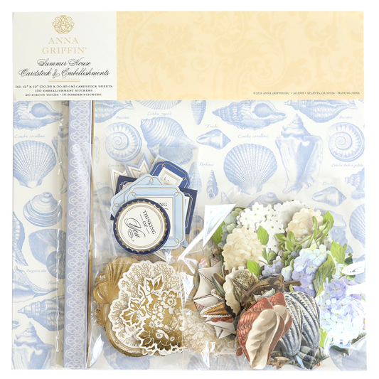 The Summer House Cardstock and Embellishments set includes blue seashell patterned paper, floral cutouts, tags, and nautical accents—ideal for coastal scrapbooking projects—all presented in attractive packaging.