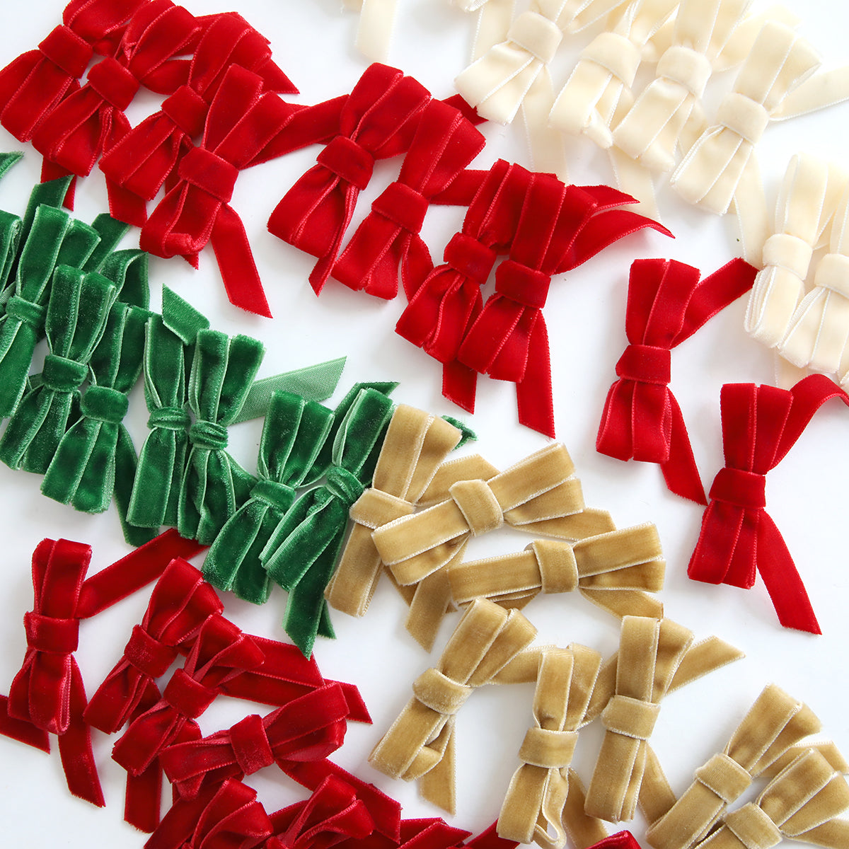 Velvet Double Bows in red, green, gold, and ivory are arranged in clusters on a white background—ideal for card making and holiday crafts.