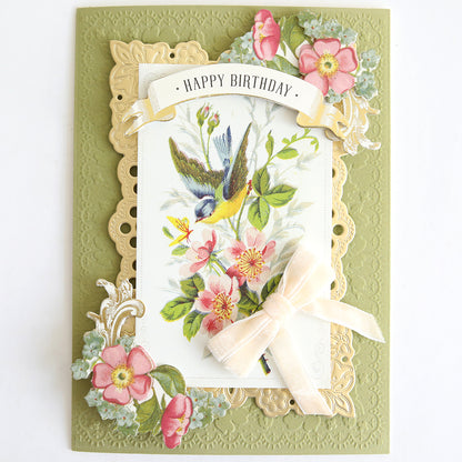 Give your next card making project a touch of inspiration with this elegant design featuring Velvet Double Bows, gold framing, delicate pink flowers, a charming bird illustration, and a beautiful floral motif. "Happy Birthday" is elegantly written at the top.