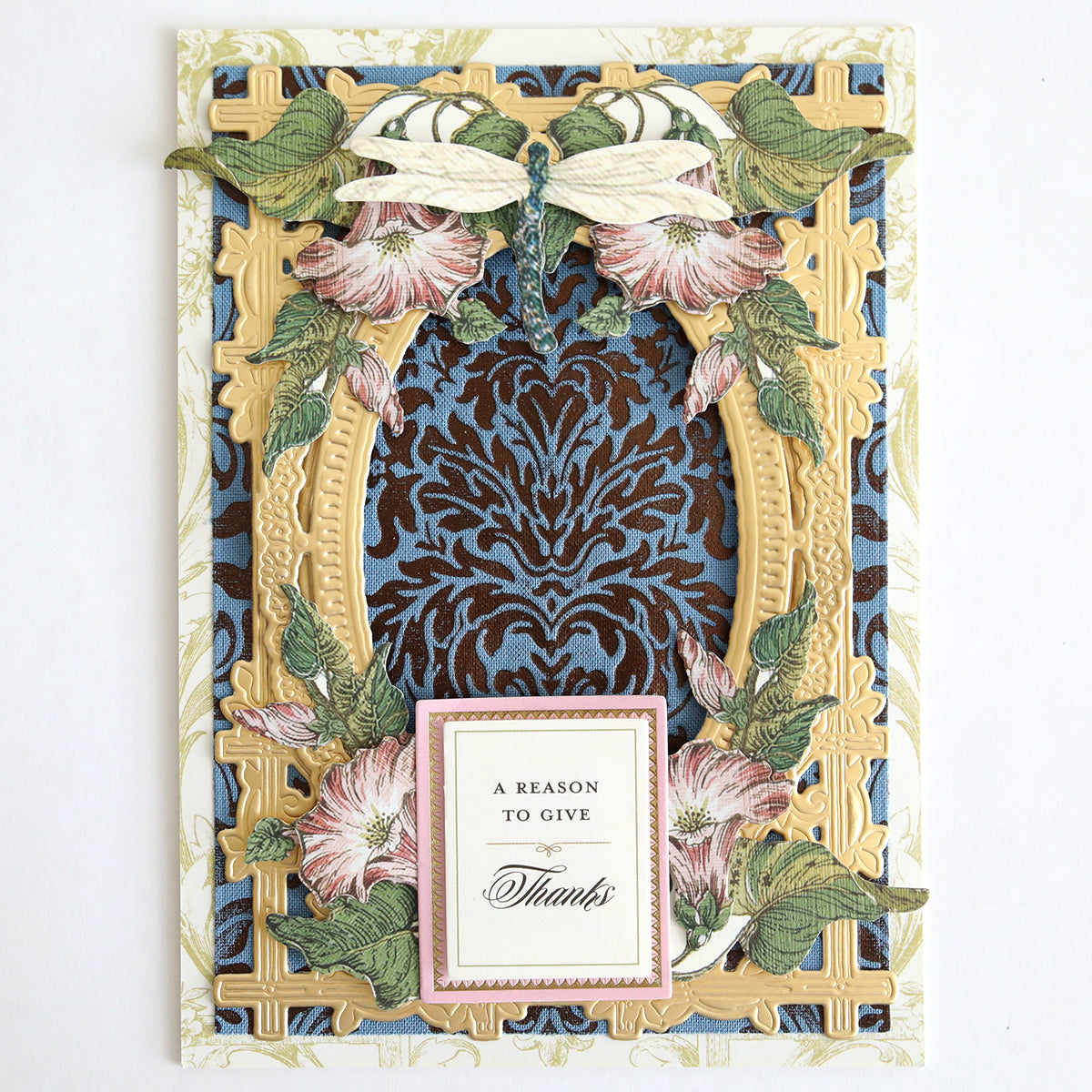 Handcrafted with the Perfect Palette Fall Foil, this ornate card features a golden frame, floral and dragonfly accents, a blue patterned background, and a label reading “A reason to give thanks.” Its elegant details are perfect for autumn paper crafting.