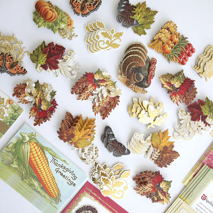The Fall Thanksgiving Postcards and Embellishments set features an assortment of autumn-themed paper cutouts—including turkeys, leaves, butterflies, and vegetables—arranged on a white surface with greeting cards in the corners. This collection is perfect for creating festive autumn paper crafts or adding a charming seasonal touch to your Thanksgiving postcards.