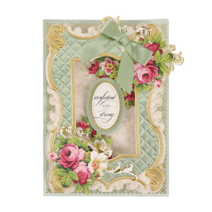 Ornate greeting card featuring a green quilted pattern, pink flowers, gold accents, and striking 3D Cottage Roses Embellishments, finished with a green ribbon bow. An oval label reading “confident AND strong” in elegant cursive sits at the center, framed by beautiful floral details for added charm.