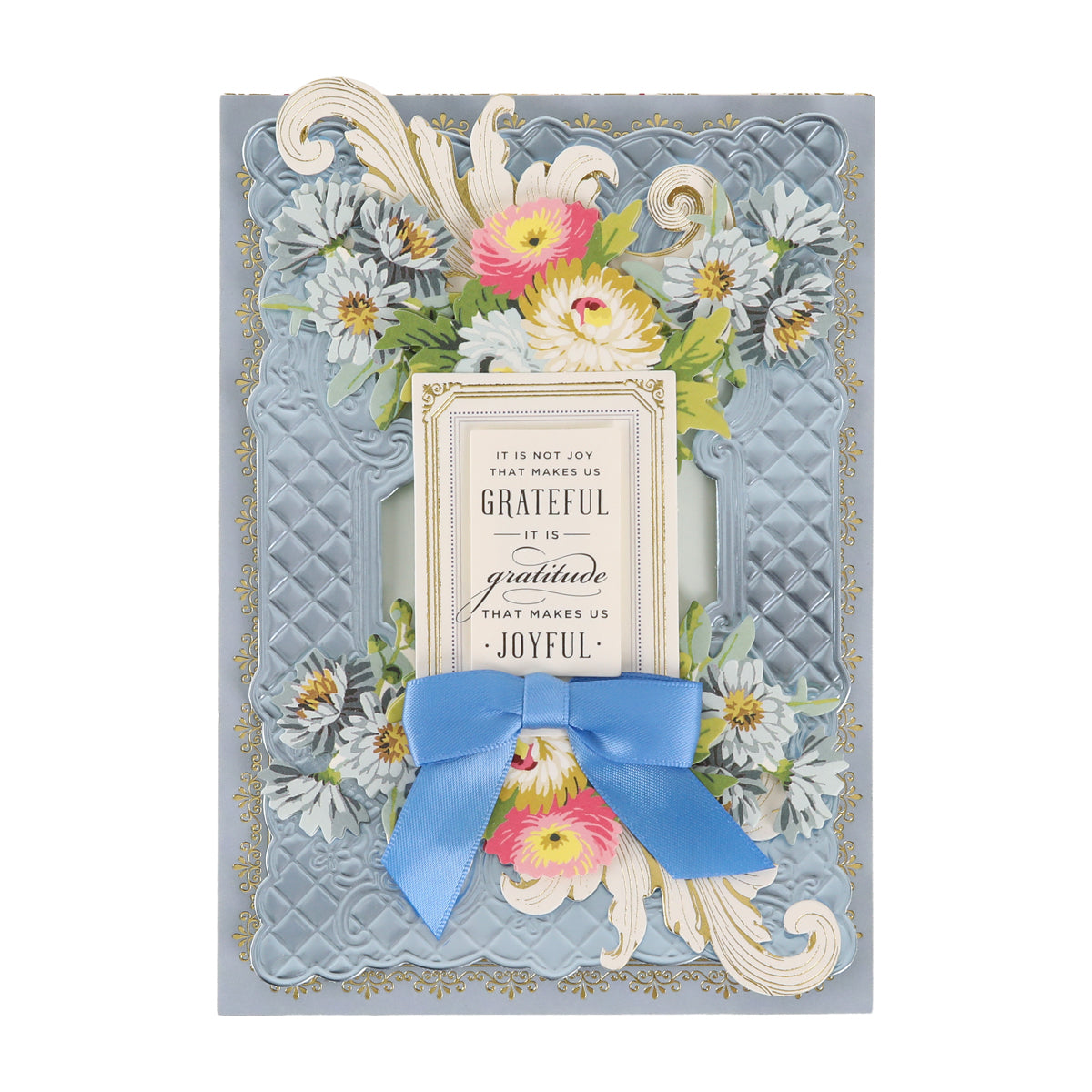 A decorative card adorned with floral designs and an elegant blue ribbon features the heartfelt message: “It is not joy that makes us grateful, it is gratitude that makes us joyful.” Cottage Roses Embellishments add a charming touch, making this card perfect for any special occasion.
