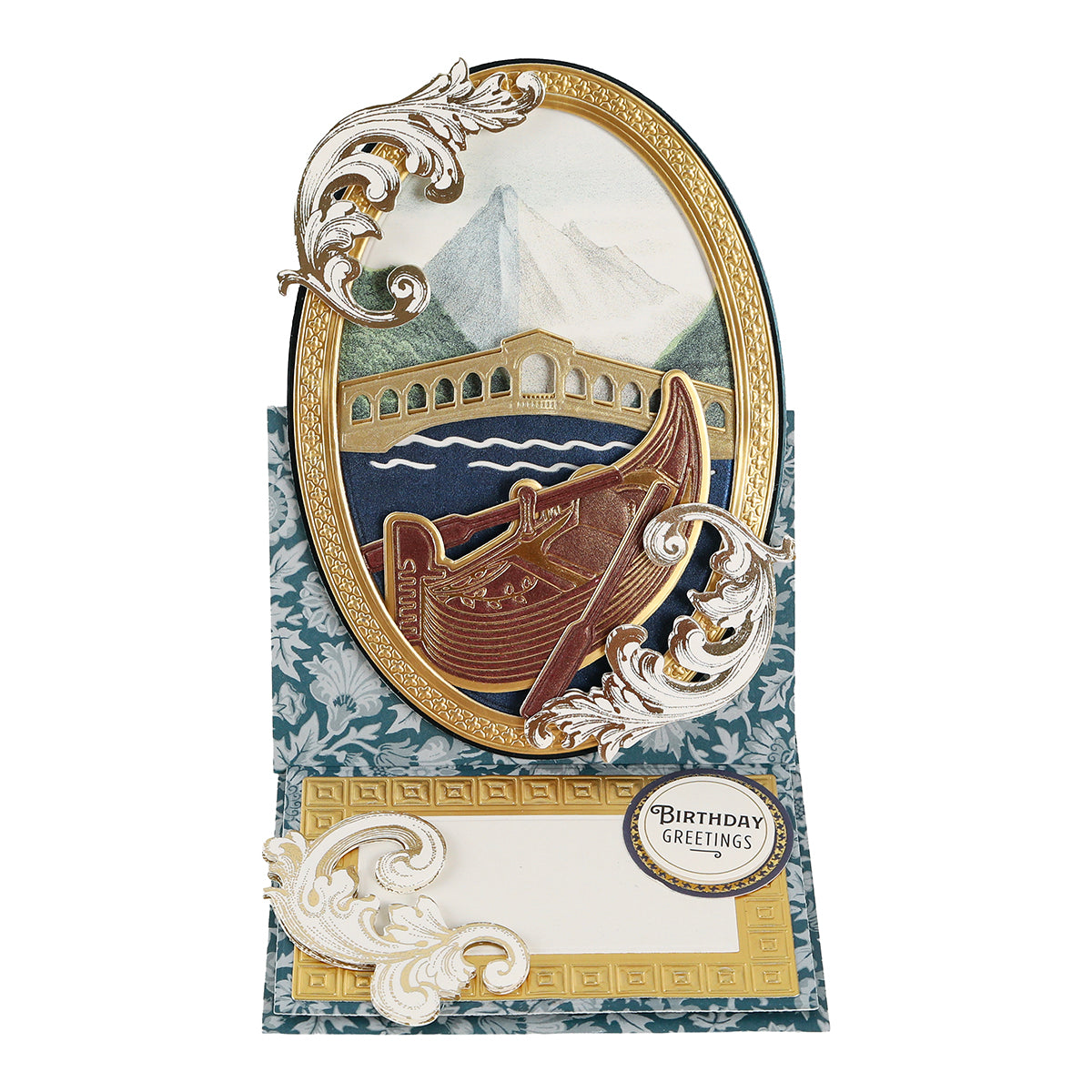 Showcasing the Gondola 3D Scene Dies, this pop-up card features a mountain, bridge, and boat nestled within an ornate oval frame. Crafted with dimensional die cuts from the set, it is embellished with Venice-inspired paper crafting accents and finished with a “Birthday Greetings” label and elegant decorative patterns.