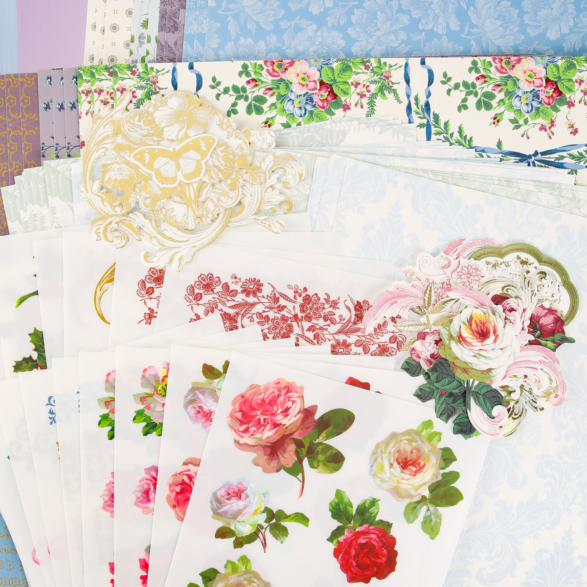 Assorted sheets of Anna Griffin | Create Fall 2026 decorative floral and patterned paper, featuring intricate rose and butterfly designs, are artfully layered in an overlapping display—perfect for sparking inspiration in our craft classes and nurturing a vibrant creative community as we look forward to the upcoming season.