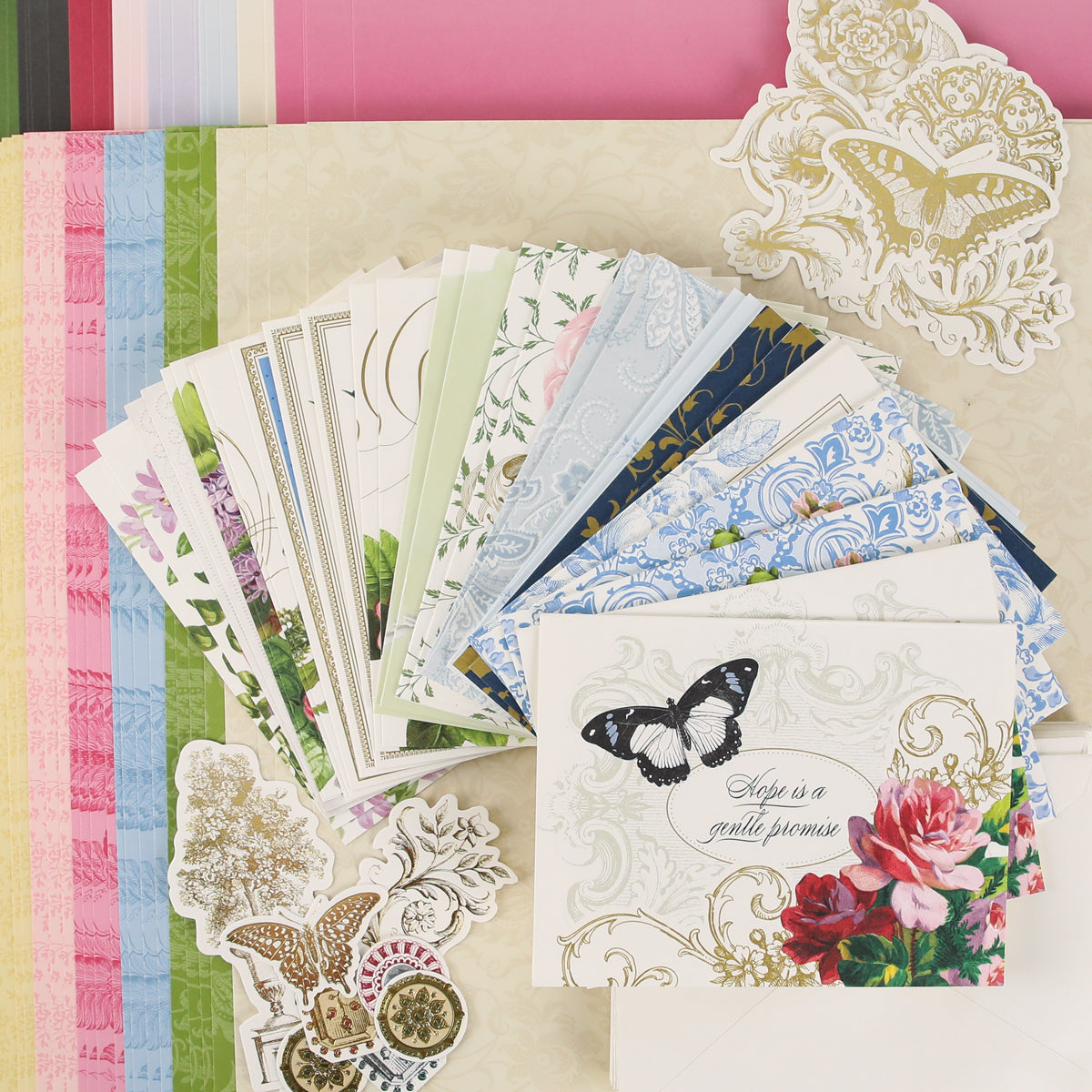 A colorful assortment of patterned papers, floral and butterfly-themed cards, and decorative stickers from Anna Griffin | Create Fall 2026 are arranged on a tabletop, inviting you to join our craft classes and connect with a vibrant creative community as we prepare for the season.