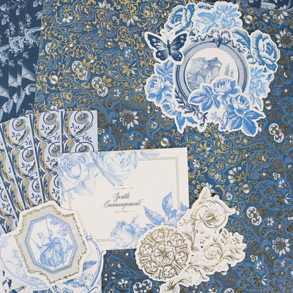 Anna Griffin | Create Fall 2026 features assorted blue and gold decorative papers with floral and butterfly motifs, ornate patterns, and a card reading “Gently Encouragement,” beautifully arranged in a flat lay—ideal inspiration for craft classes or anyone looking to connect with a creative community.