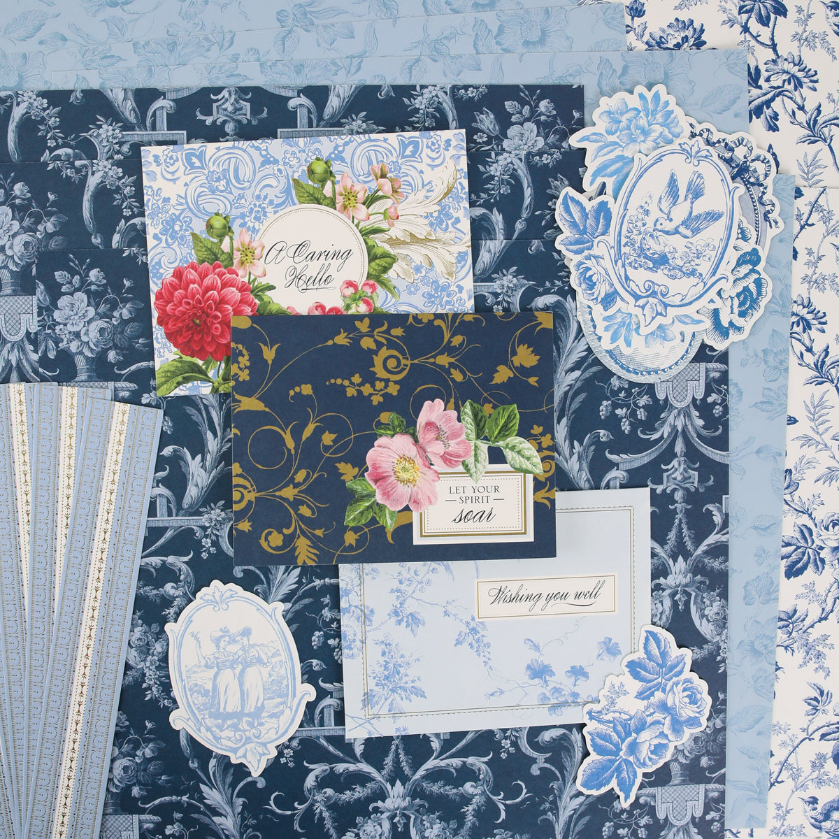 Assorted blue and white floral-patterned papers and greeting cards featuring elegant flower and bird motifs are artfully layered for a stunning decorative display—ideal inspiration for craft classes or anyone seeking creative community at Anna Griffin | Create Fall 2026.