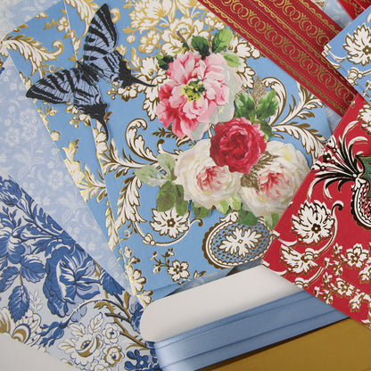 Anna Griffin | Create Fall 2026 features an inspiring selection of assorted patterned papers with floral, butterfly, and ornamental designs in blue, red, gold, and white hues—ideal for your next creative community project or craft classes. This collection also includes coordinating blue and red ribbon rolls arranged on a flat surface—everything you need to create standout masterpieces for Fall 2026.
