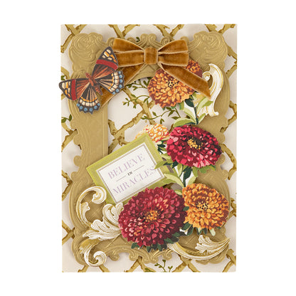 Greeting card featuring Fall Flower Embellishments, a gold ornate frame, butterfly, gold velvet bow, and “BELIEVE IN MIRACLES.” inside the frame.