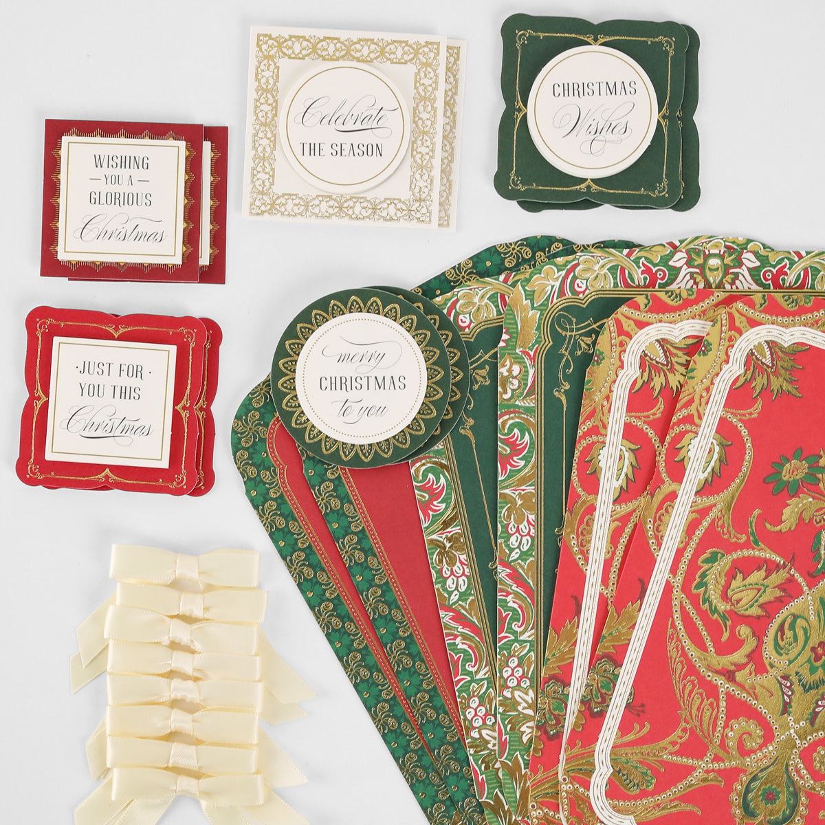 Simply Merry Christmas Card Making Kit supplies—patterned paper, greeting labels, and cream bows—arranged on a white surface.