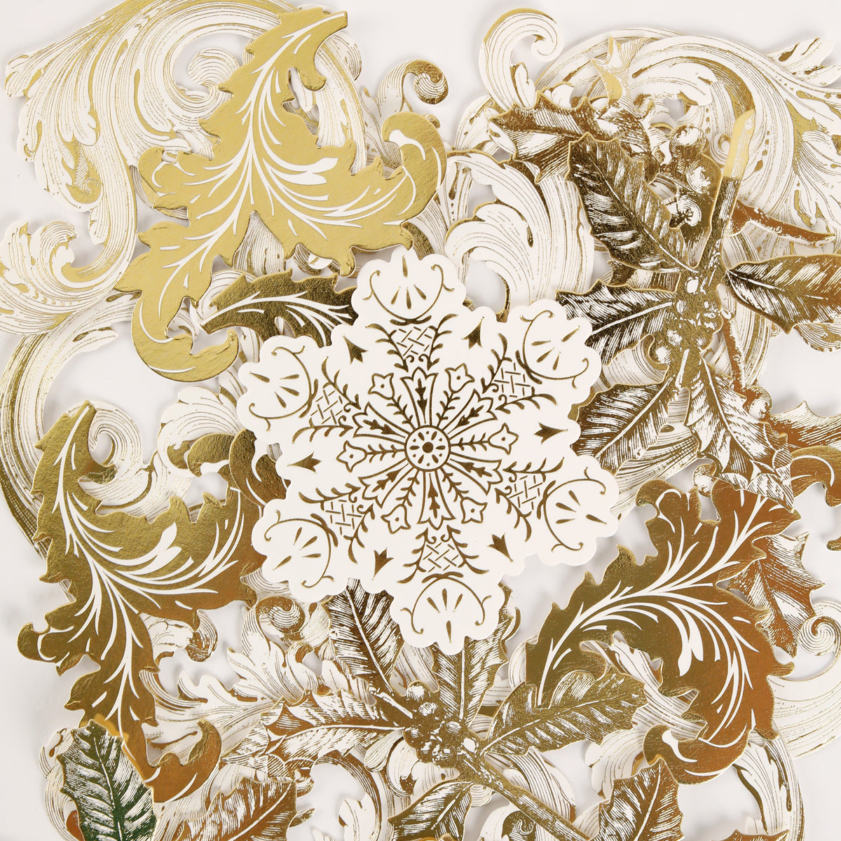 The Simply Merry Christmas Card Making Kit features gold and white paper cutouts with leaf and snowflake designs, perfect for your festive holiday card creations.