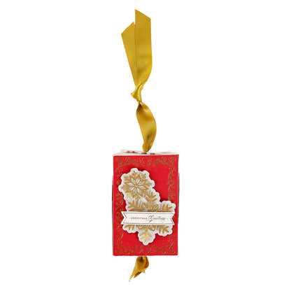 Red rectangular ornament with gold floral design and “Christmas Greetings” text—ideal for holiday crafts or as an accent to the Christmas Grace Advent Calendar.