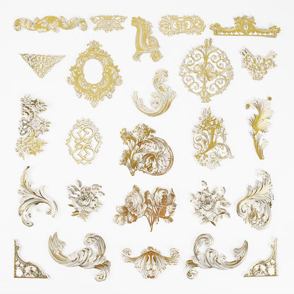 Gold Foil Flourish Stickers feature gold and white ornate baroque-style decorative elements and floral motifs arranged in rows on a white background, perfect for adding metallic embellishments to scrapbook projects.